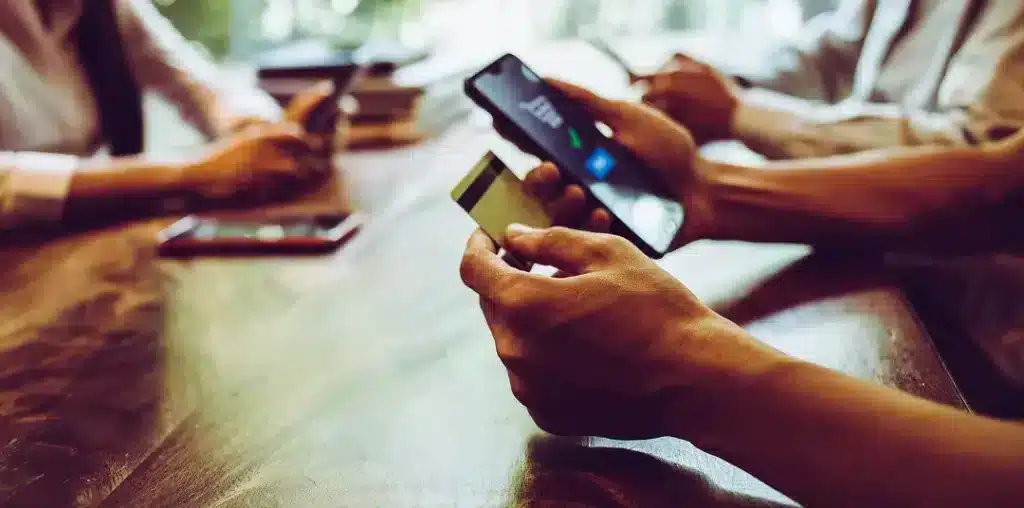 persona realizando un pago digital con tarjeta y celular en una mesa de trabajo